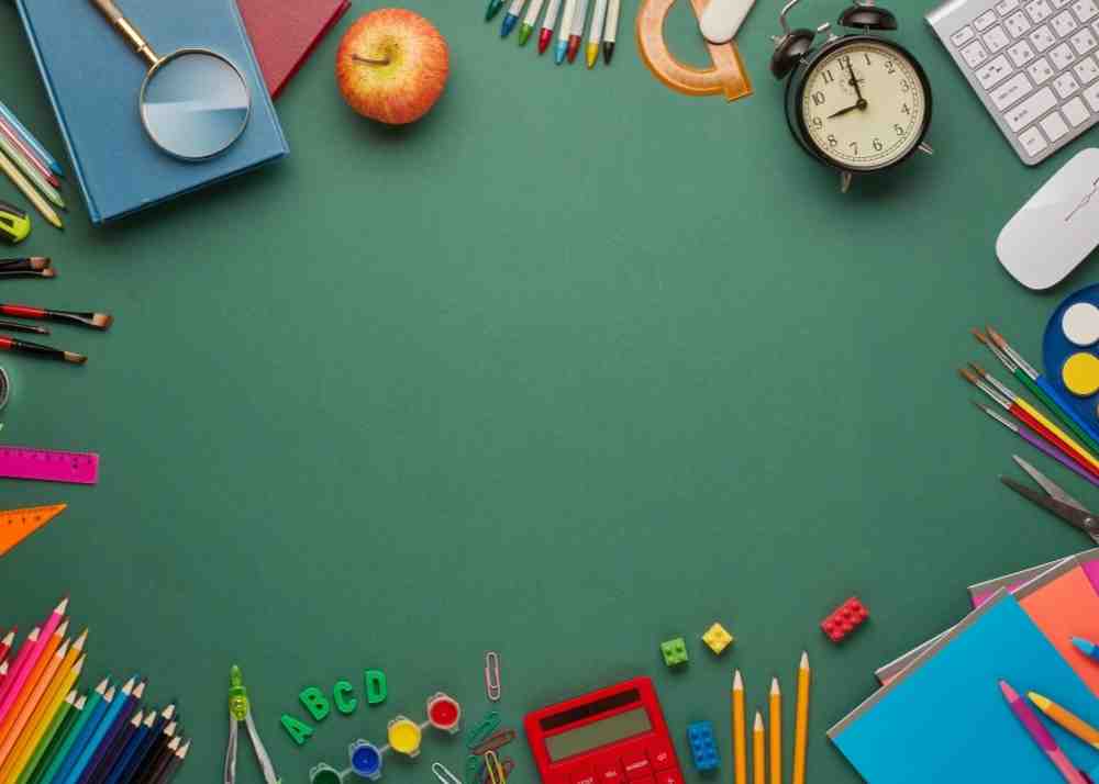 A variety of school supplies on a green table.